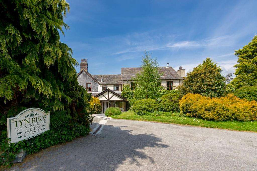 he green gardens and stone exterior of Tyn Rhos Country House near Caernarfon.