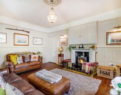 Living room with leather chesterfields and a wood burner at Llwynhelig House, near Cowbridge