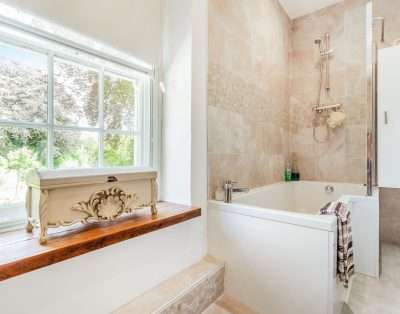 Bathroom with a bath, shower and garden views at Llwynhelig House, Vale of Glamorgan