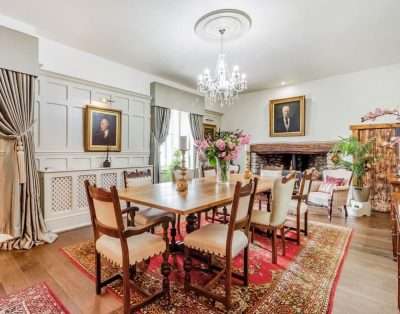 Elegant dining room with chandelier and inglenook fireplace at Llwynhelig House, near Cowbridge