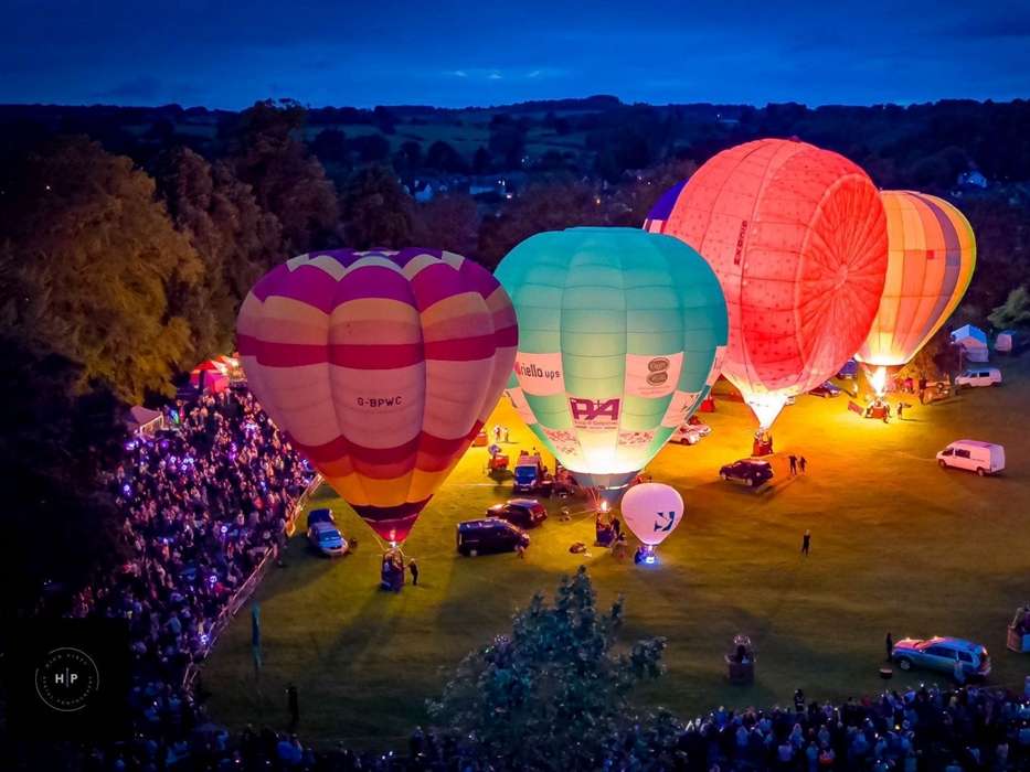 Hot air balloons glowing at night on the grass during the Oswestry Balloon Carnival at Cae Glas Park