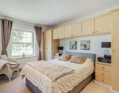 Double bedroom with fitted wardrobes and a wicker chair at Quail Cottage, near Cowbridge