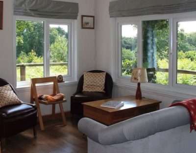 Living room with leather tub chairs and garden views at The Garden House, near Monmouth