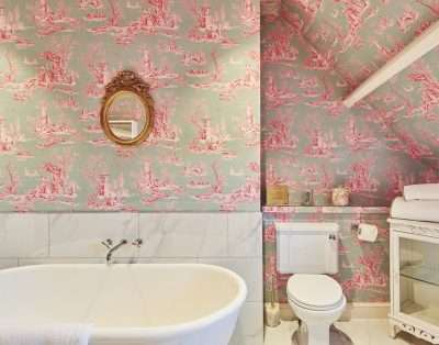 Toile-wallpapered bathroom with a roll-top bath at Valley Manor, near Cowbridge