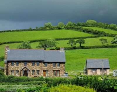 The stone farmhouse at Ferryside Farm surrounded by green fields and hedgerows