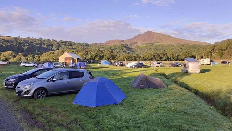 Tents and cars on the camping field at Dolgam in evening light with Moel Siabod behind