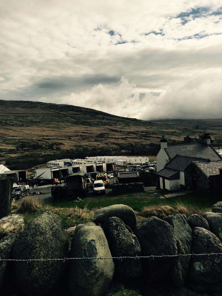 Campervans and cars parked beside the stone farmhouse at Gwern Gof Isaf, Capel Curig