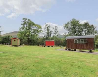 The field at Tilly caravan hut, with three huts spread out and the hills behind