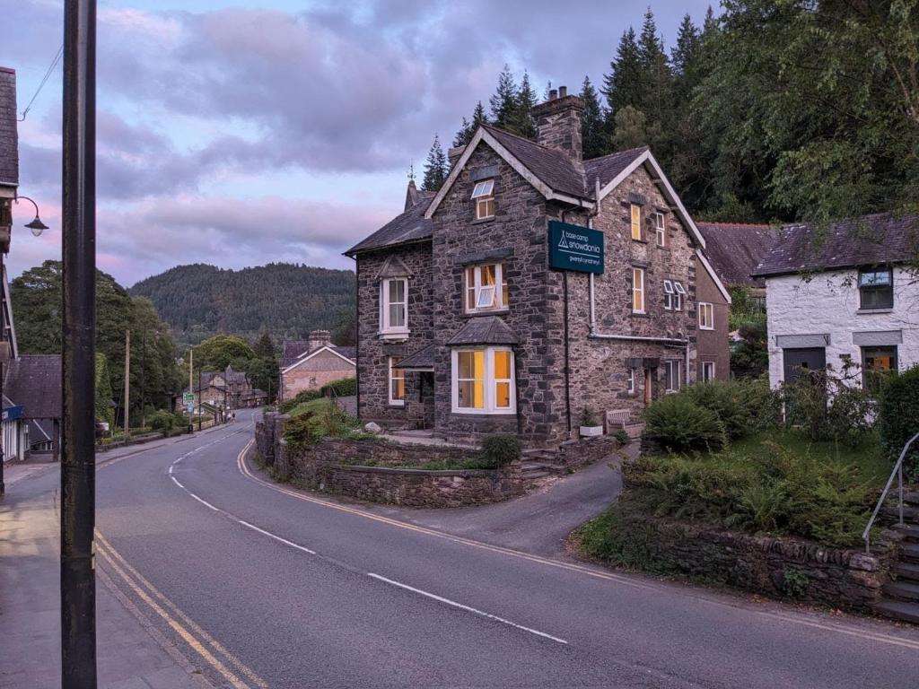 Base Camp Snowdonia hostel, a stone building on Holyhead Road in Betws-y-Coed, lit at dusk