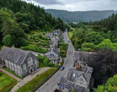 Aerial view of Betws-y-Coed showing Base Camp Snowdonia hostel among the slate roofs and trees