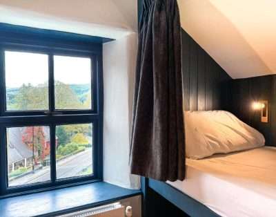 Bunk bed beside a deep window seat at Base Camp Snowdonia, looking out over Betws-y-Coed