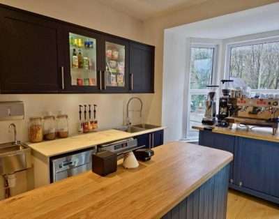 Kitchen counter at Base Camp Snowdonia with a wooden worktop, coffee machine and dark cabinets