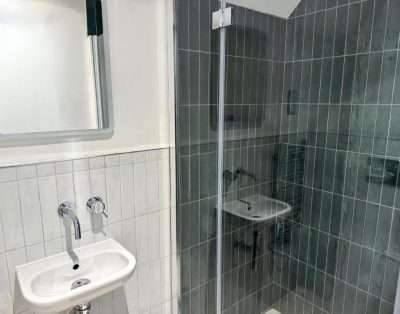 Tiled shower room at Base Camp Snowdonia with a basin and a dark-tiled walk-in shower